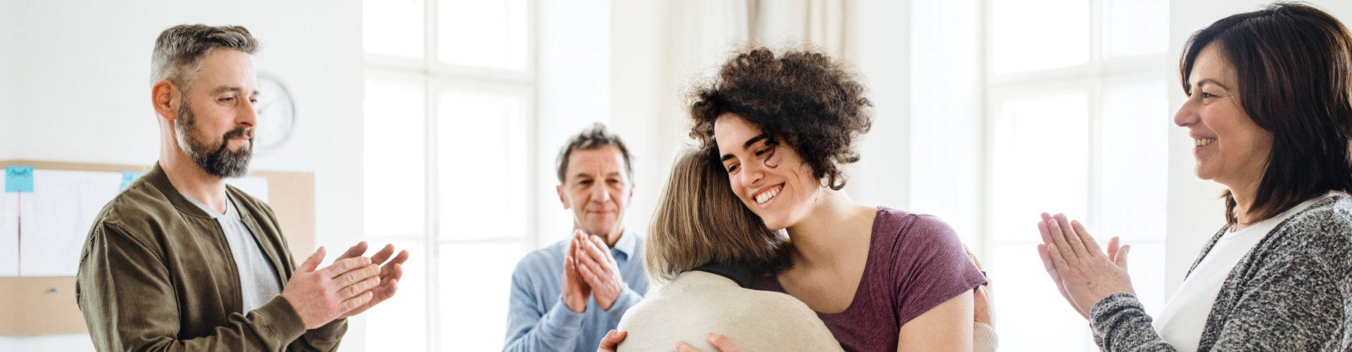 a photo of a woman hugging another woman while there are three people clapping