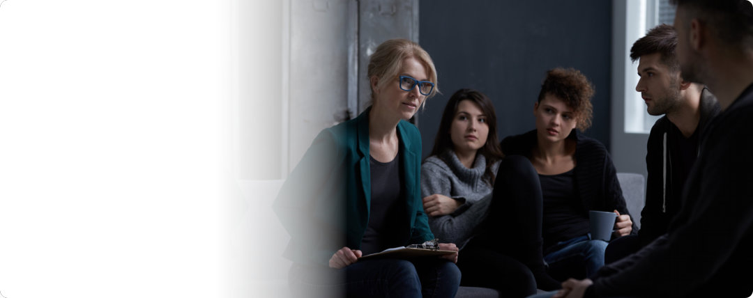 a woman with glasses talking while people around her are listening